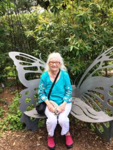 Bonnie Buckley Maldonado sits on a metal bench shaped like butterfly wings